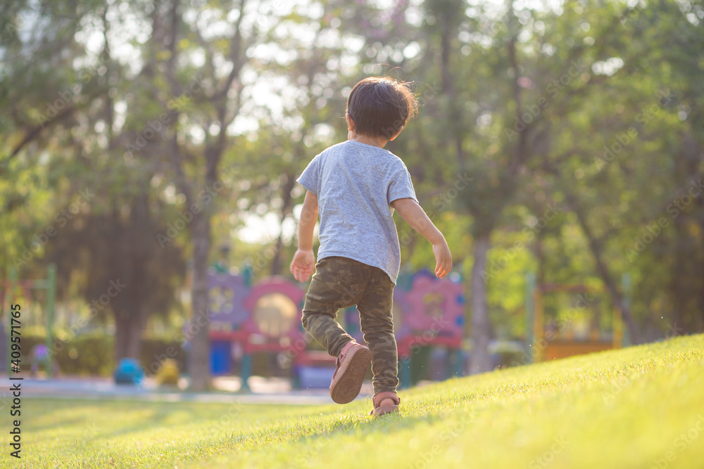 Little asian boy playing outdoor kid having fun enjoy walking on green grass of playground