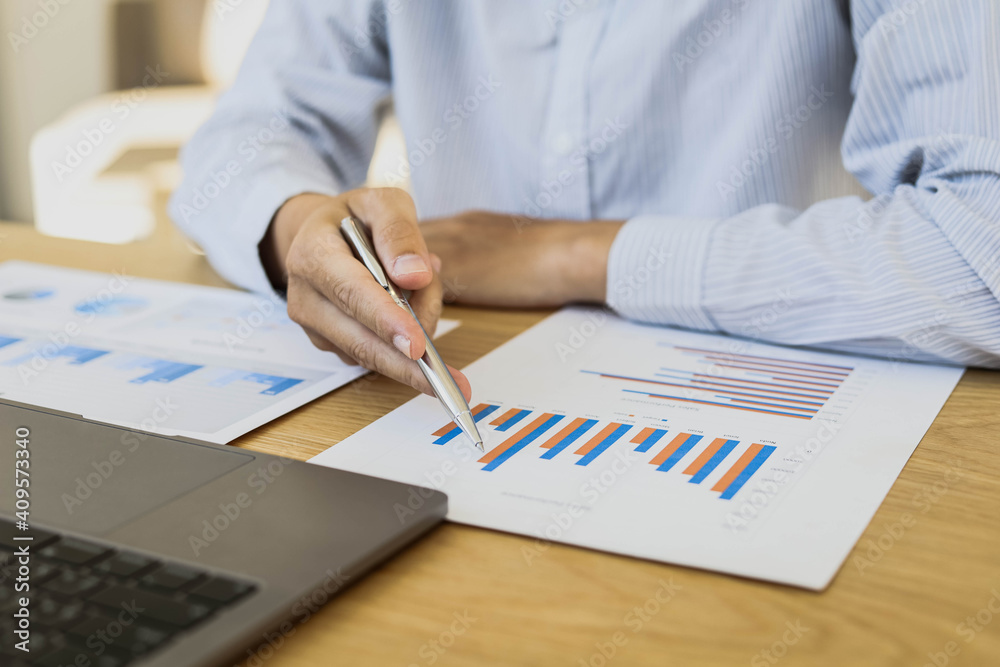 A businessman is reading a monthly sales graph in his office. He checks the sales volume of each salesperson to summarize the commission. Sales management concept. A businessman is reading a monthly sales graph in his office. He checks the sales volume of each salesperson to summarize the commission. Sales management concept.