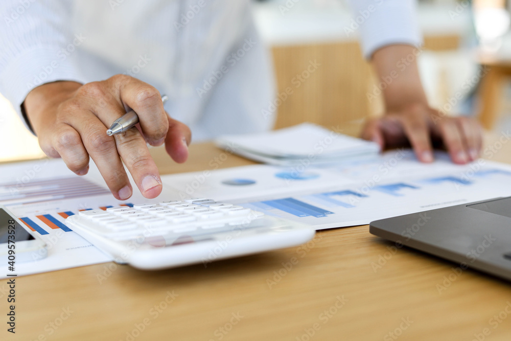 Managers are calculating by using a calculator to validate the company's income to bring it to the management meeting. He sits and works in his private office. Management concept. Managers are calculating by using a calculator to validate the company's income to bring it to the management meeting. He sits and works in his private office. Management concept.