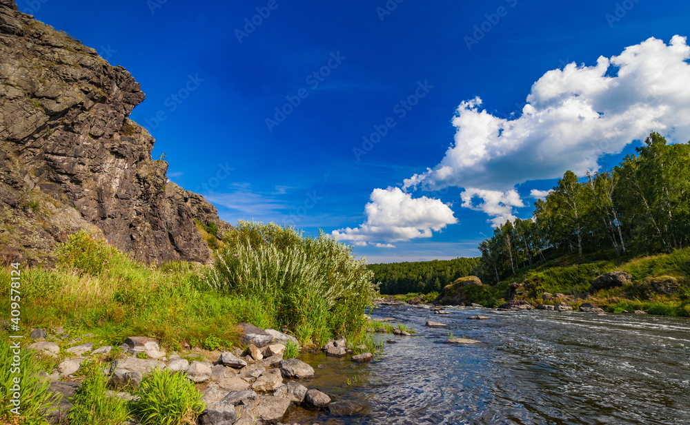 Fast river with rocky banks, overgrown with trees in summer Fast river with rocky banks, overgrown with trees in summer