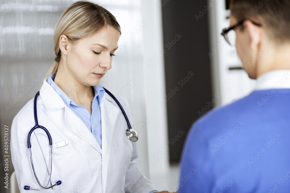 Friendly female doctor and patient man discussing current health examination while sitting in clinic. Perfect medical service in hospital. Medicine and healthcare concept Friendly female doctor and patient man discussing current health examination while sitting in clinic. Perfect medical service in hospital. Medicine and healthcare concept