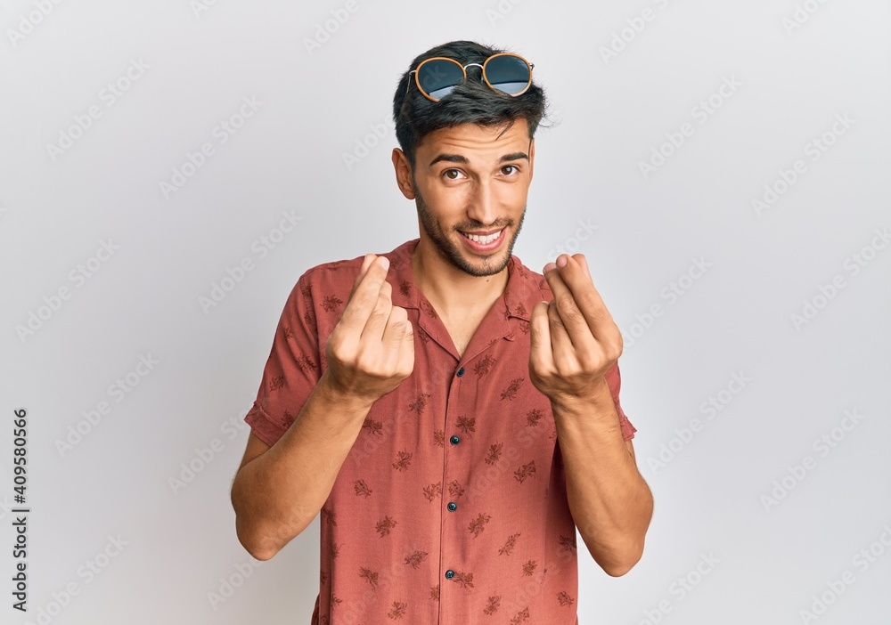 Naklejka premium Young handsome man wearing casual summer clothes doing money gesture with hands, asking for salary payment, millionaire business