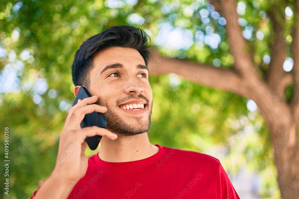 Young latin man smiling happy talking on the smartphone walking at the city. Young latin man smiling happy talking on the smartphone walking at the city.