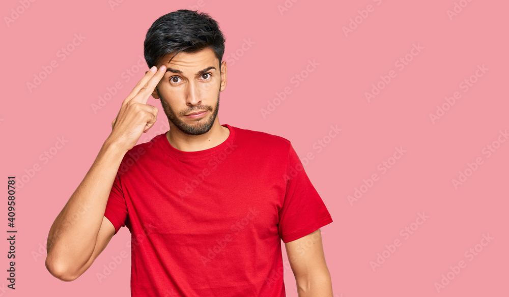 Young handsome man wearing casual red tshirt shooting and killing oneself pointing hand and fingers to head like gun, suicide gesture. Young handsome man wearing casual red tshirt shooting and killing oneself pointing hand and fingers to head like gun, suicide gesture.