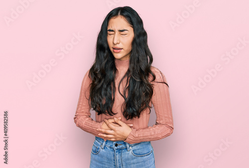 Hispanic teenager girl with dental braces wearing casual clothes with hand on stomach because nausea, painful disease feeling unwell. ache concept. © Krakenimages.com