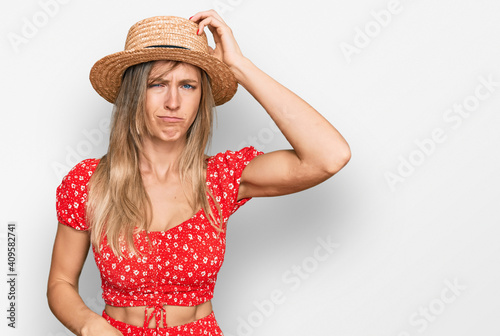 Beautiful caucasian woman wearing summer hat confuse and wonder about question. uncertain with doubt, thinking with hand on head. pensive concept.
