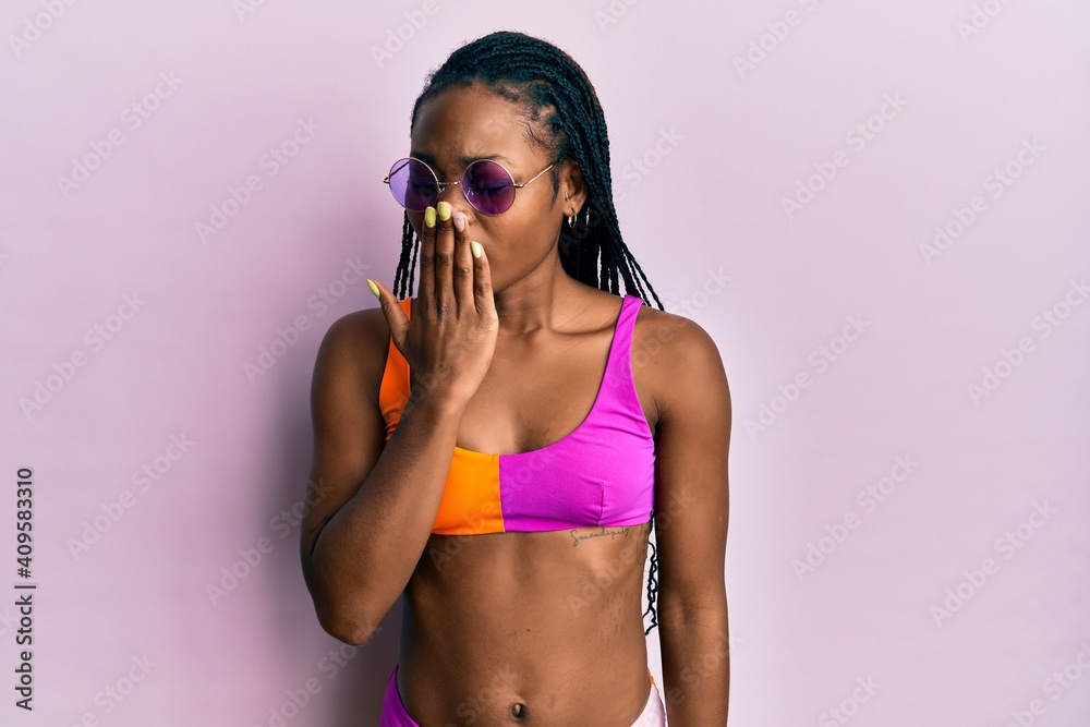 Obraz premium Young african american woman wearing bikini and sunglasses bored yawning tired covering mouth with hand. restless and sleepiness.
