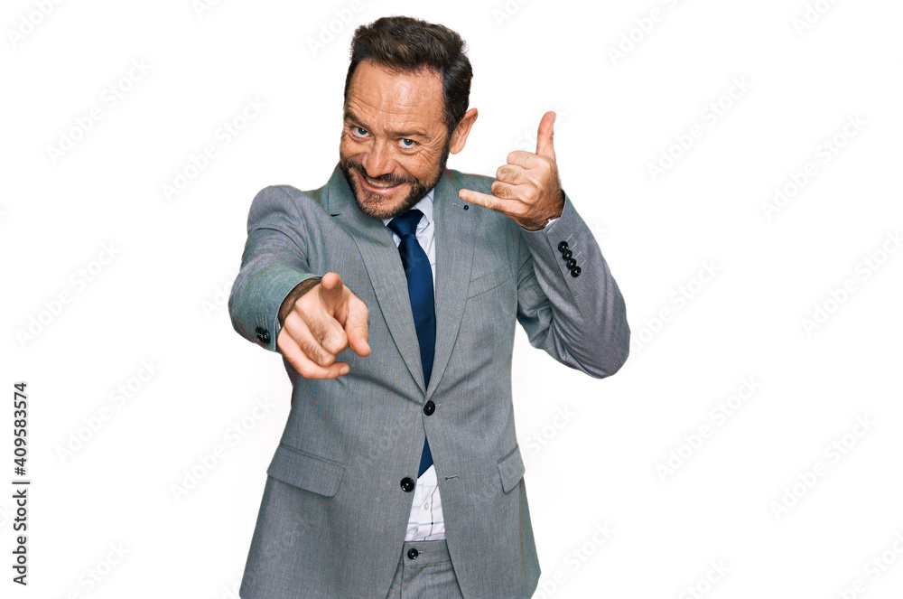Middle age man wearing business clothes smiling doing talking on the telephone gesture and pointing to you. call me. Middle age man wearing business clothes smiling doing talking on the telephone gesture and pointing to you. call me.