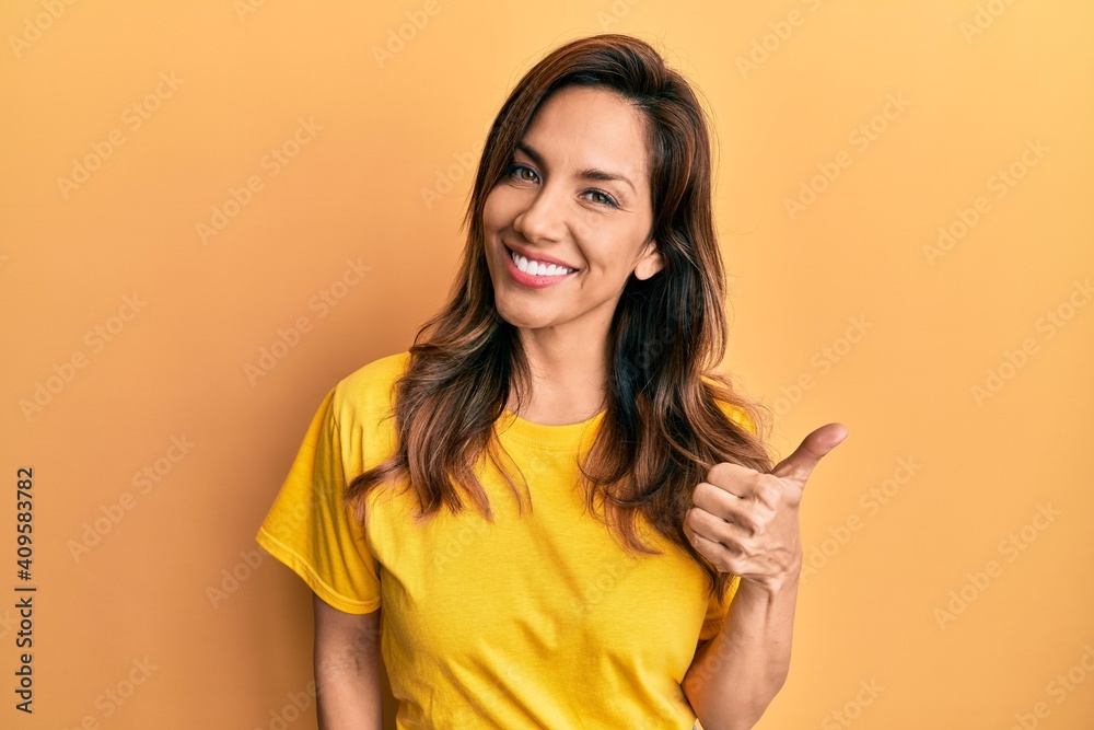 Young latin woman wearing casual clothes doing happy thumbs up gesture with hand. approving expression looking at the camera showing success. Young latin woman wearing casual clothes doing happy thumbs up gesture with hand. approving expression looking at the camera showing success.
