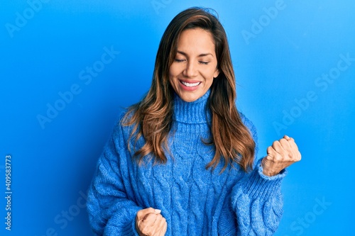 Young latin woman wearing casual winter sweater celebrating surprised and amazed for success with arms raised and eyes closed