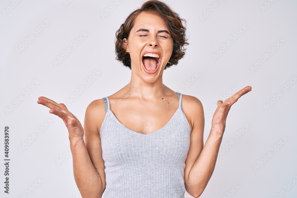 Young hispanic woman wearing casual clothes celebrating mad and crazy for success with arms raised and closed eyes screaming excited. winner concept Young hispanic woman wearing casual clothes celebrating mad and crazy for success with arms raised and closed eyes screaming excited. winner concept