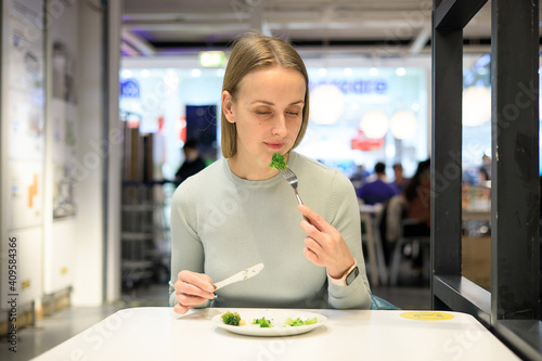 Woman eating broccoli in cafe