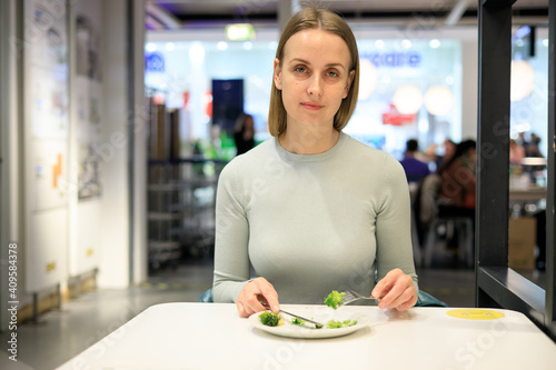 Woman eating broccoli in cafe
