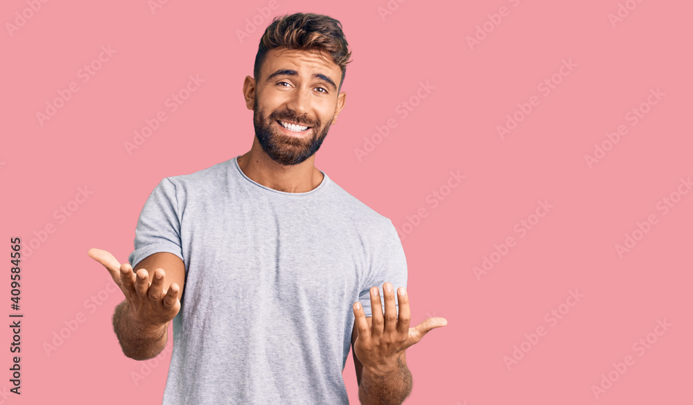 Young hispanic man wearing casual clothes smiling cheerful with open arms as friendly welcome, positive and confident greetings - obrazy, fototapety, plakaty 