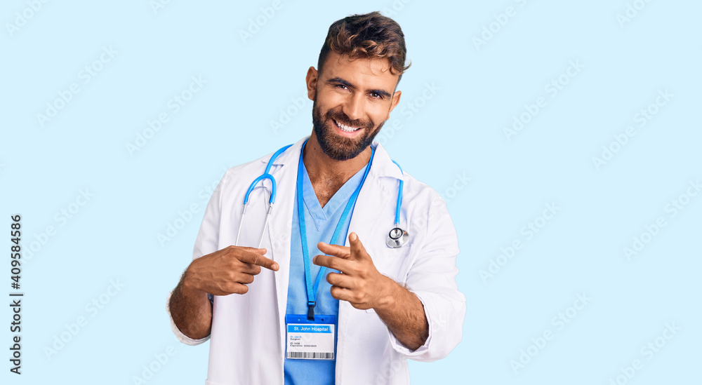 Young hispanic man wearing doctor uniform and stethoscope pointing fingers to camera with happy and funny face. good energy and vibes. Young hispanic man wearing doctor uniform and stethoscope pointing fingers to camera with happy and funny face. good energy and vibes.