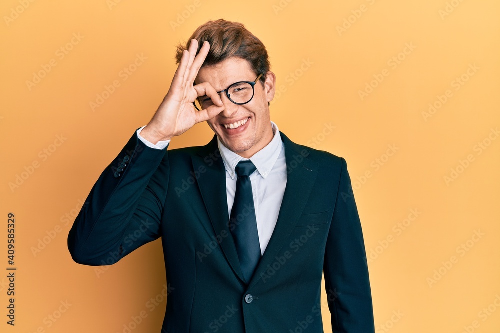 Handsome caucasian man wearing business suit and tie doing ok gesture with hand smiling, eye looking through fingers with happy face. Handsome caucasian man wearing business suit and tie doing ok gesture with hand smiling, eye looking through fingers with happy face.