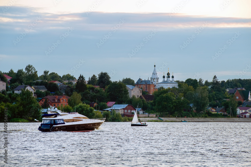 Obraz premium Speedboat and sailing boat on a summer evening at sunset on the Volga River