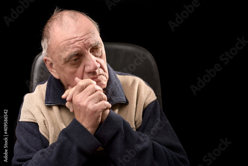 portrait vieil homme recroqueviller de chagrin dans son fauteuil sur fond noir