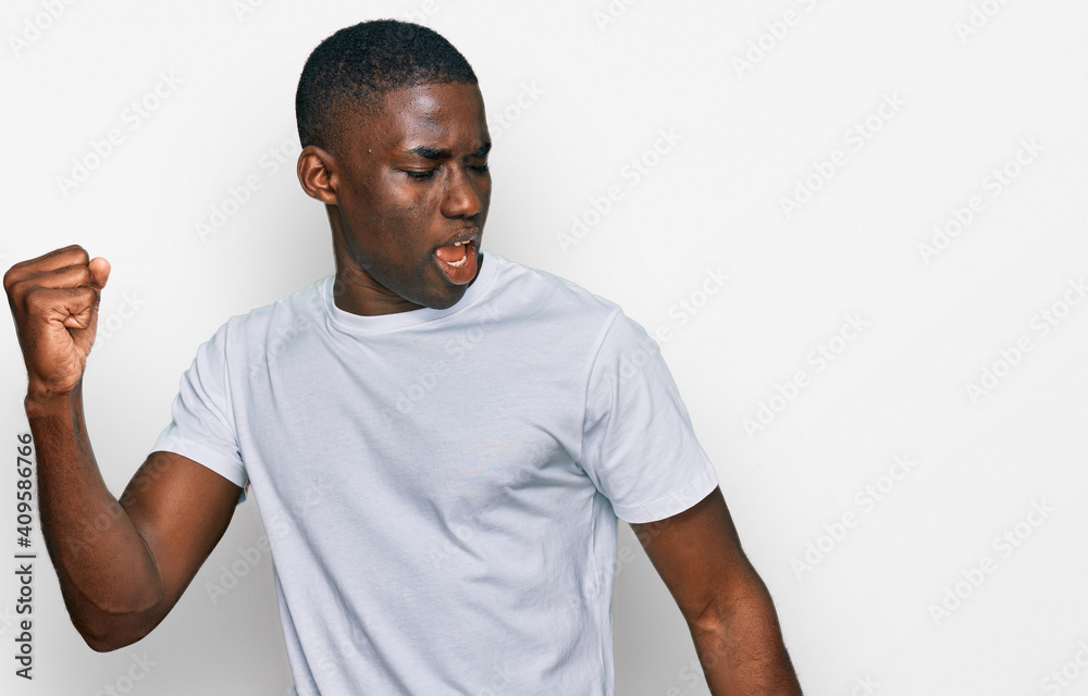 Young african american man wearing casual white t shirt dancing happy and cheerful, smiling moving casual and confident listening to music Young african american man wearing casual white t shirt dancing happy and cheerful, smiling moving casual and confident listening to music
