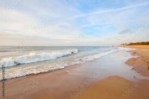 Baltic sea shore (sand dunes) at sunset. Soft sunlight, clear sky, glowing clouds, waves. Idyllic seascape. Ziemelu Mols, Liepaja, Latvia, Europe. Travel destinations, ecotourism, nature photo