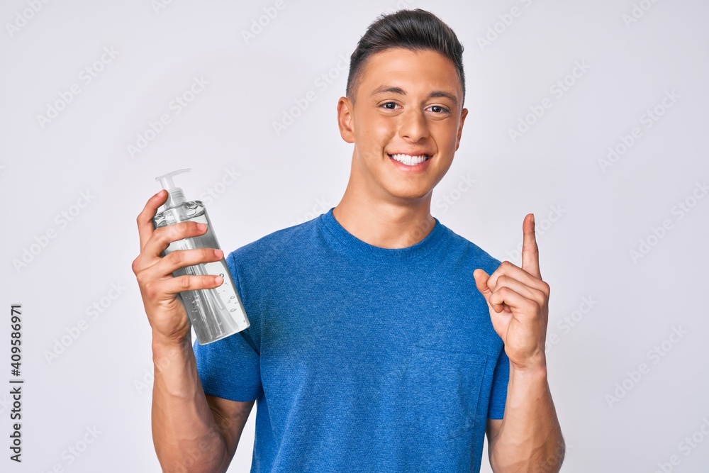 Young hispanic boy using hand sanitizer gel surprised with an idea or question pointing finger with happy face, number one Young hispanic boy using hand sanitizer gel surprised with an idea or question pointing finger with happy face, number one
