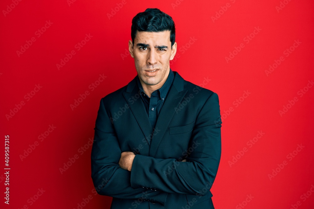 Obraz premium Handsome hispanic business man with arms crossed gesture clueless and confused expression. doubt concept.