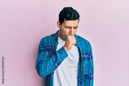 Handsome hispanic man wearing casual clothes feeling unwell and coughing as symptom for cold or bronchitis. health care concept.