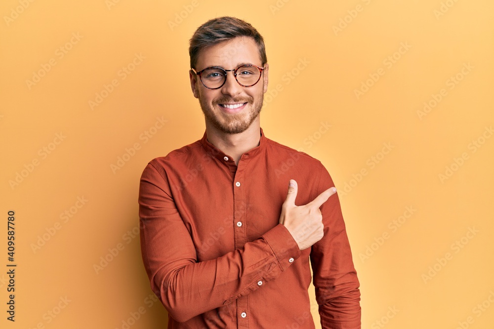 Handsome caucasian man wearing casual clothes and glasses smiling cheerful pointing with hand and finger up to the side