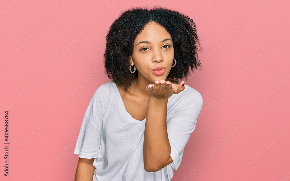 Young african american girl wearing casual clothes looking at the camera blowing a kiss with hand on air being lovely and sexy. love expression.