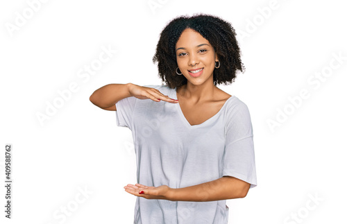 Young african american girl wearing casual clothes gesturing with hands showing big and large size sign, measure symbol. smiling looking at the camera. measuring concept.