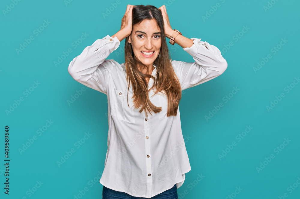 Young beautiful woman wearing casual clothes crazy and scared with hands on head, afraid and surprised of shock with open mouth Young beautiful woman wearing casual clothes crazy and scared with hands on head, afraid and surprised of shock with open mouth