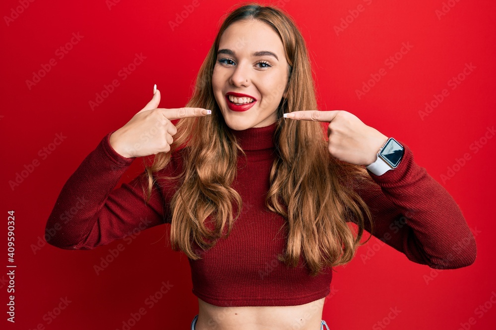 Young blonde woman wearing turtleneck sweater smiling cheerful showing and pointing with fingers teeth and mouth. dental health concept. Young blonde woman wearing turtleneck sweater smiling cheerful showing and pointing with fingers teeth and mouth. dental health concept.