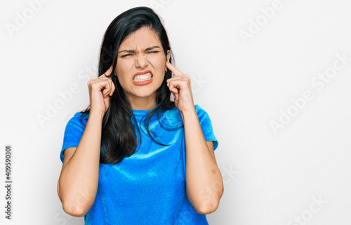 Young hispanic woman wearing casual clothes covering ears with fingers with annoyed expression for the noise of loud music. deaf concept. © Krakenimages.com