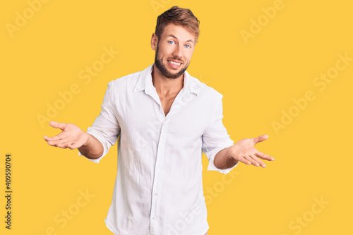 Young caucasian man wearing casual clothes clueless and confused expression with arms and hands raised. doubt concept.