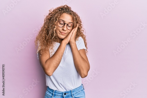 Beautiful caucasian teenager girl wearing white t-shirt over pink background sleeping tired dreaming and posing with hands together while smiling with closed eyes.