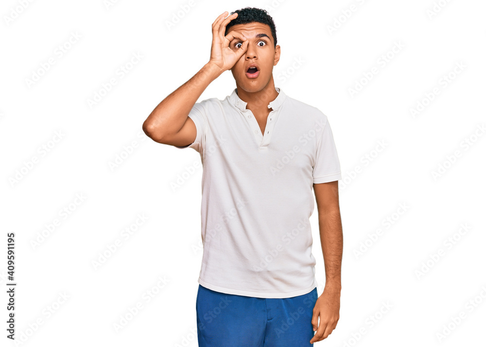 Young arab man wearing casual clothes doing ok gesture shocked with surprised face, eye looking through fingers. unbelieving expression. Young arab man wearing casual clothes doing ok gesture shocked with surprised face, eye looking through fingers. unbelieving expression.