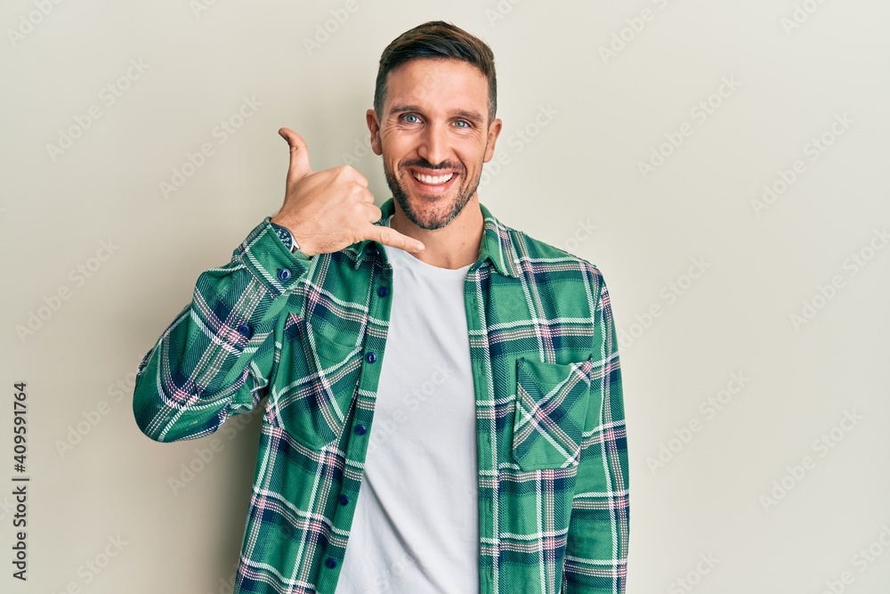 Handsome man with beard wearing casual clothes smiling doing phone gesture with hand and fingers like talking on the telephone. communicating concepts.