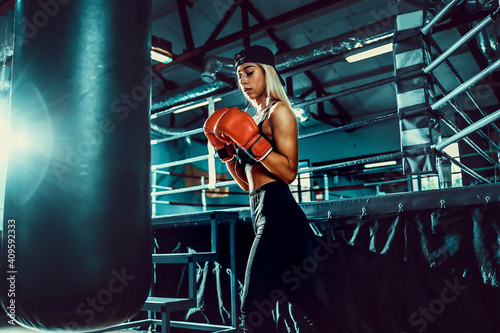 Attractive Female Boxer Training by hitting boxing punching bag