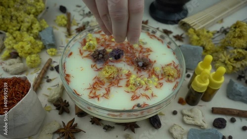 Woman's hand puts ingredients to the glassware for preparation domestic cosmetics. Preparation of natural bath for skin. Alternative medicine, organic cosmetics, aromatherapy and natural care concept.