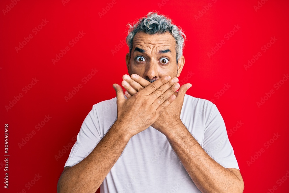 Middle age grey-haired man wearing casual white tshirt shocked covering mouth with hands for mistake. secret concept.