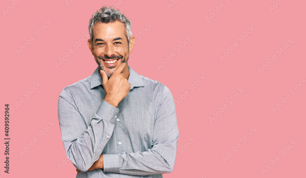 Fototapeta premium Middle age grey-haired man wearing casual clothes looking confident at the camera smiling with crossed arms and hand raised on chin. thinking positive.