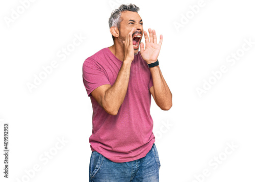 Middle age grey-haired man wearing casual clothes shouting angry out loud with hands over mouth