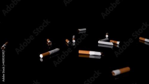 Slow-motion fall of cigarettes butts on black mirroring surface, studio-shot.