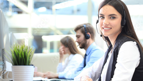 Smiling female call centre operator doing her job with a headset while looking at camera.