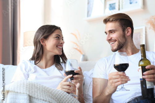 Young loving couple drinking a glass of red wine in their living room.