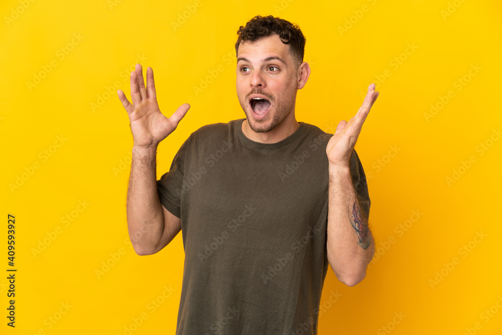 Young caucasian handsome man isolated on yellow background with surprise facial expression - obrazy, fototapety, plakaty 