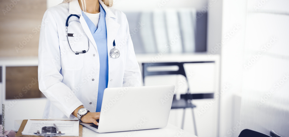 Unknown female physician using laptop computer, close-up. Woman-doctor at work in clinic. Medicine concept