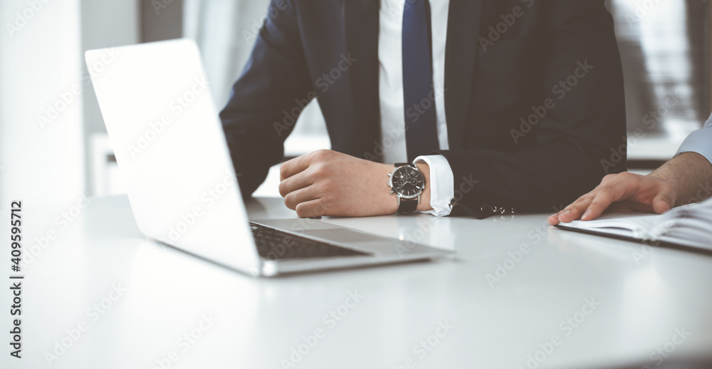 Unknown business people using laptop computer at the desk in modern office. Businessman or male entrepreneur is working with his colleague. Teamwork and partnership concept Unknown business people using laptop computer at the desk in modern office. Businessman or male entrepreneur is working with his colleague. Teamwork and partnership concept