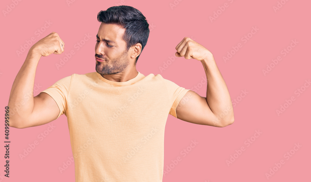 Young hispanic man wearing casual clothes showing arms muscles smiling proud. fitness concept. Young hispanic man wearing casual clothes showing arms muscles smiling proud. fitness concept.