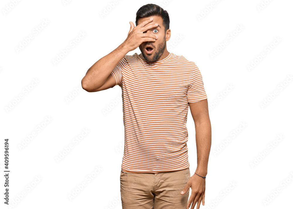 Handsome hispanic man wearing casual clothes peeking in shock covering face and eyes with hand, looking through fingers with embarrassed expression. Handsome hispanic man wearing casual clothes peeking in shock covering face and eyes with hand, looking through fingers with embarrassed expression.